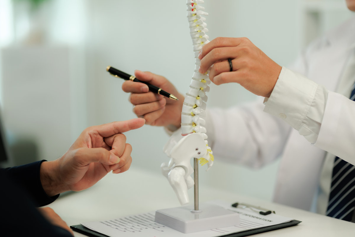 Doctor consulting with a patient suffering from back pain, offering guidance and treatment options for spinal care.